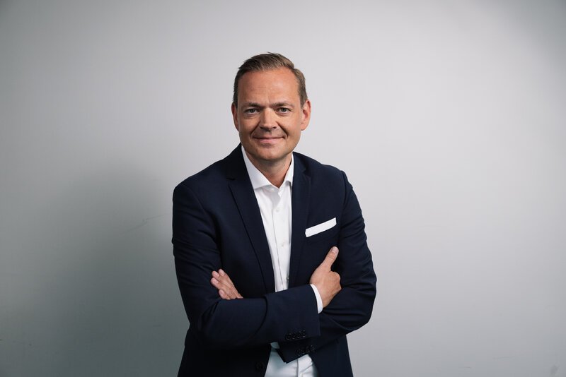 Andreas Brenner im dunklen Anzug mit verschränkten Armen